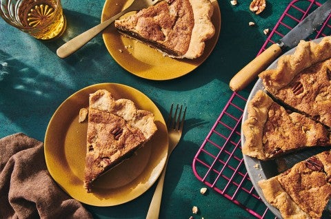 Slices of Chocolate Chip Pecan Pie on plates next to the full pie - select to zoom