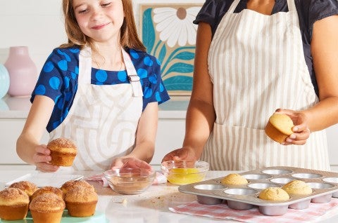 A girl baking muffins with an adult