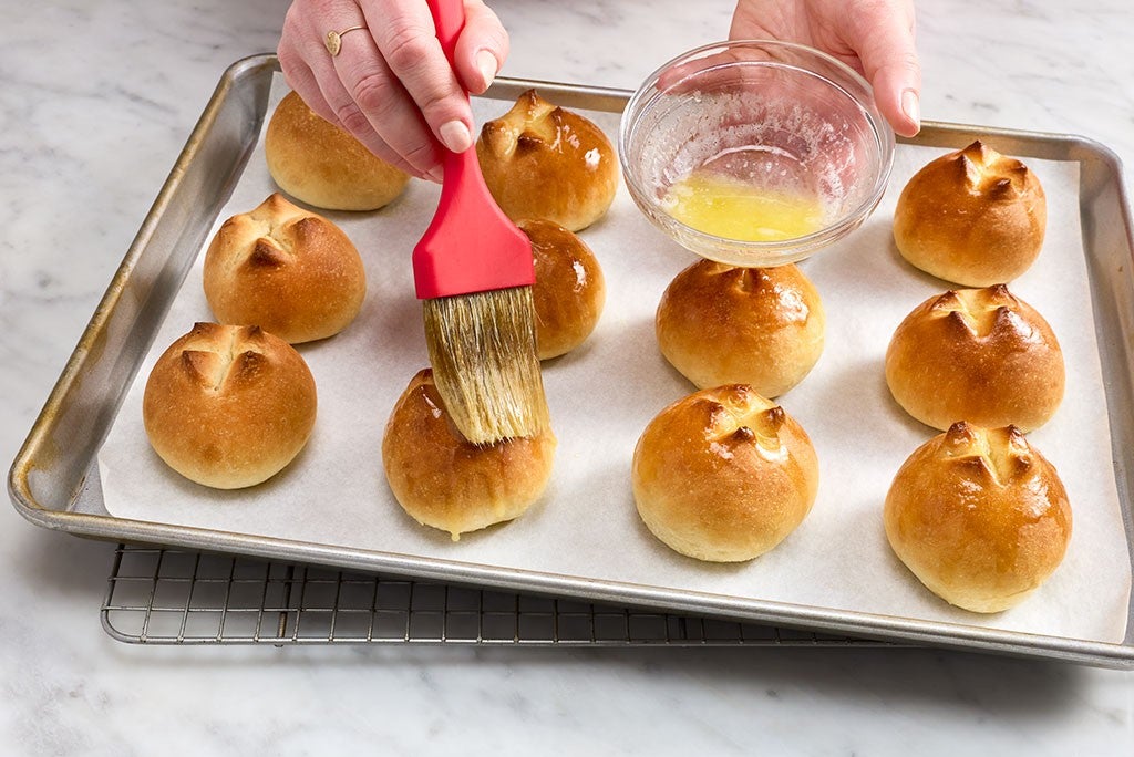 Brushing butter on the top of freshly baked buns.