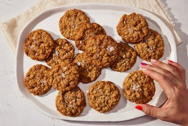 An overhead photo of Oatmeal Cookies on an oval platter for serving. The cookies have crackly tops and flaky sea salt sprinkled on them.
